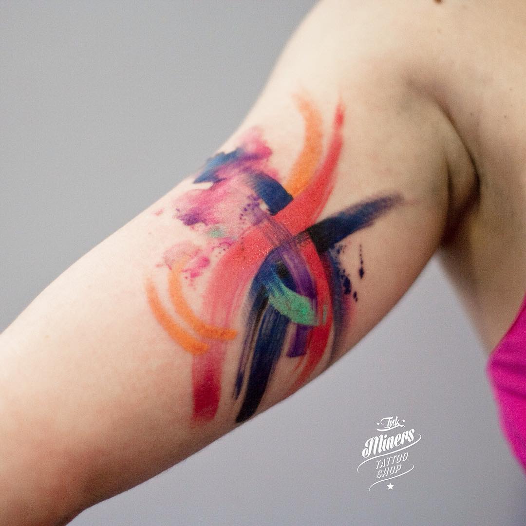 colorful brushstrokes on bicep tattoo