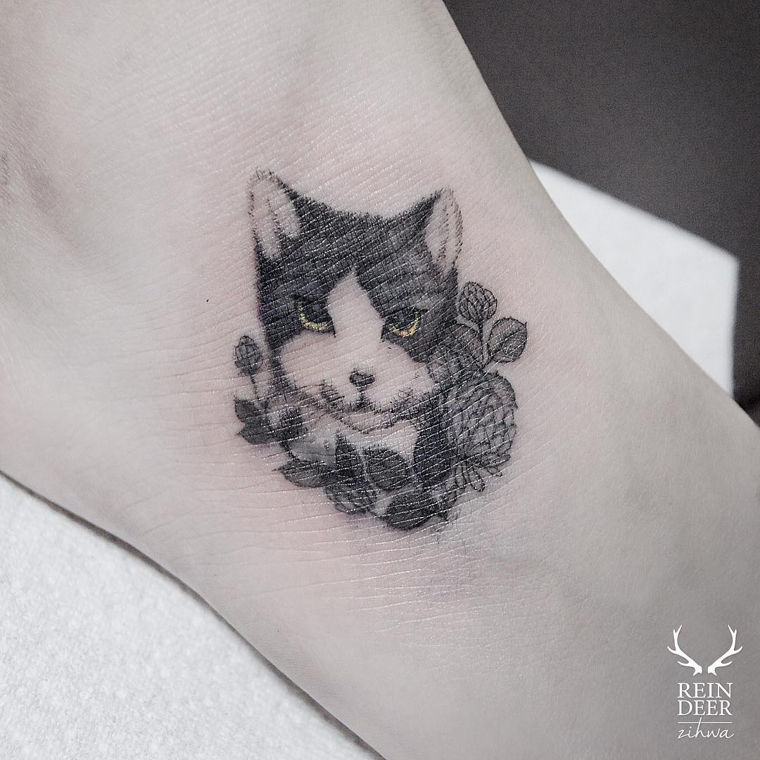 tiny head of a cat tattoo in even tinier flowers