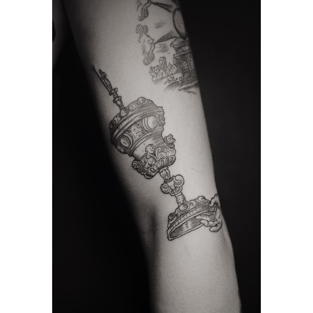 some luxury cup is depicted in this arm tattoo