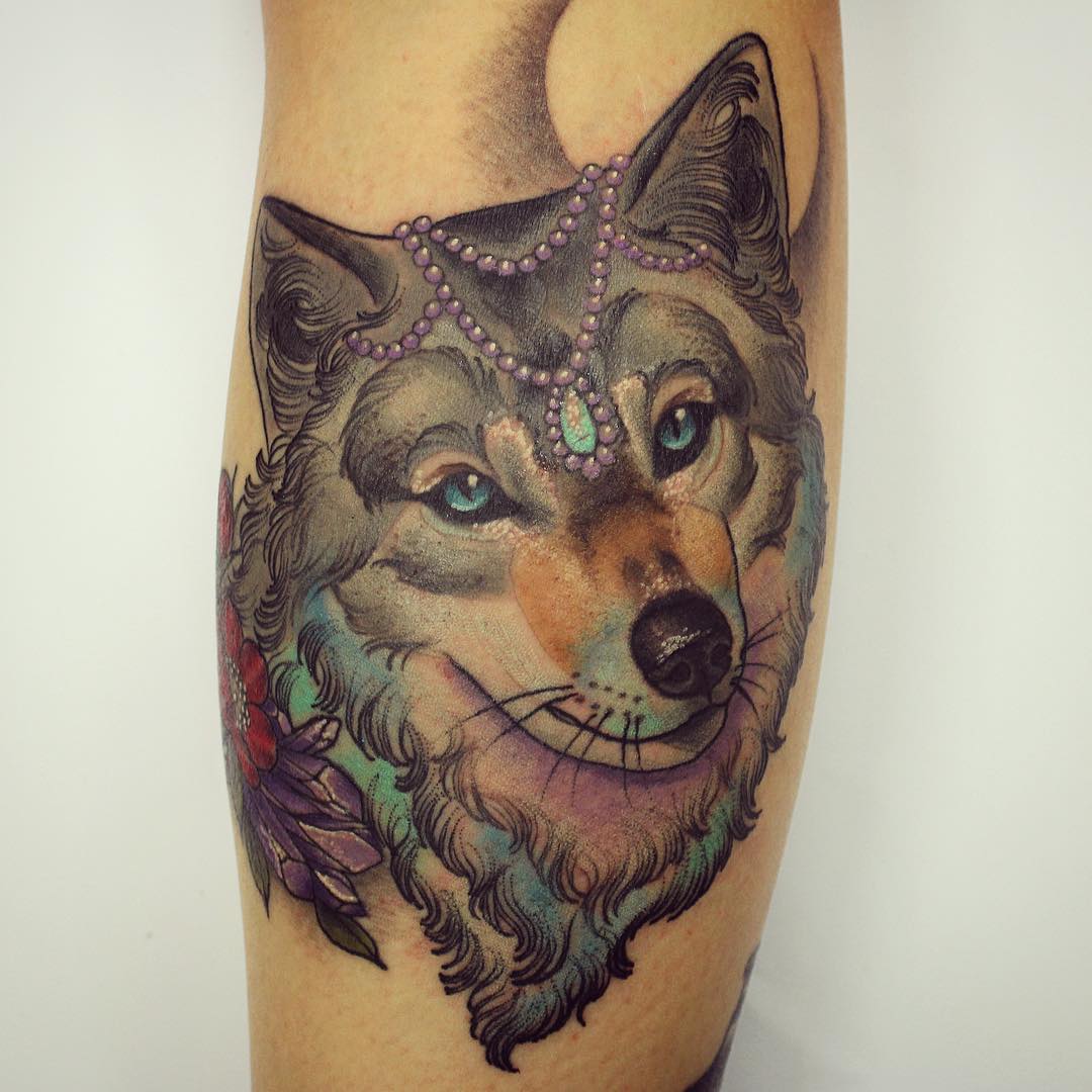 The tattoo of a lovely wolf head with some accessories on it