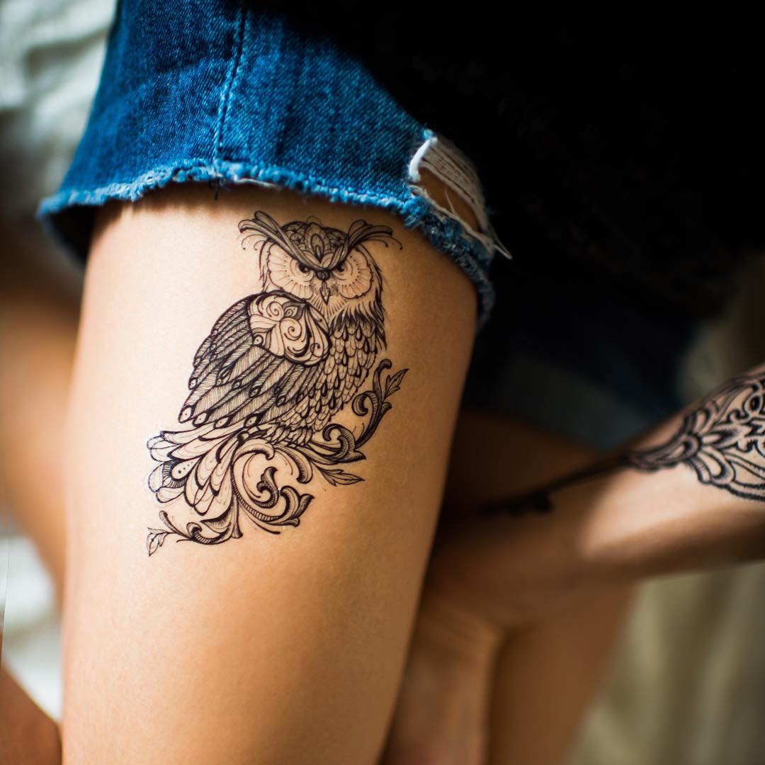 the tattoo of owl on thigh with a thin lines however with some sort of trible style patterns