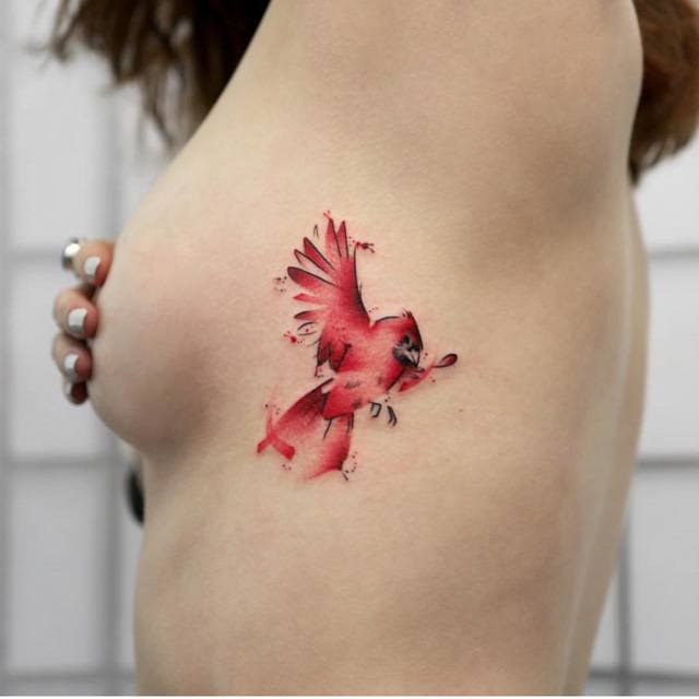 watercolor red bird tattoo on ribs