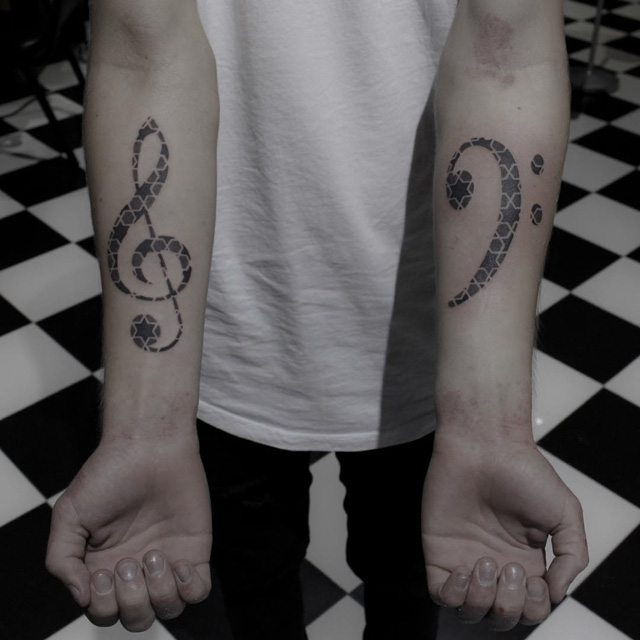 treble cle tattoo and bass clef tattoo on arms