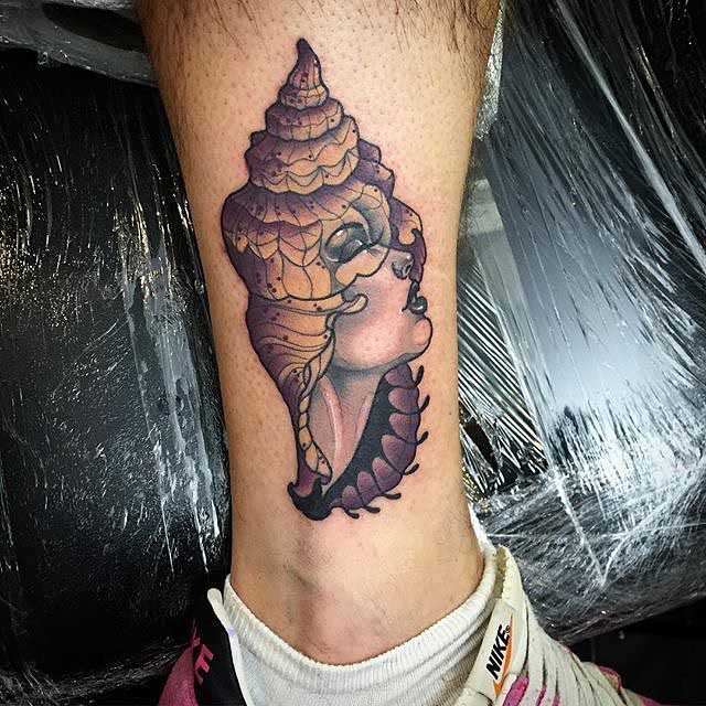 shell tattoo with face on forearm