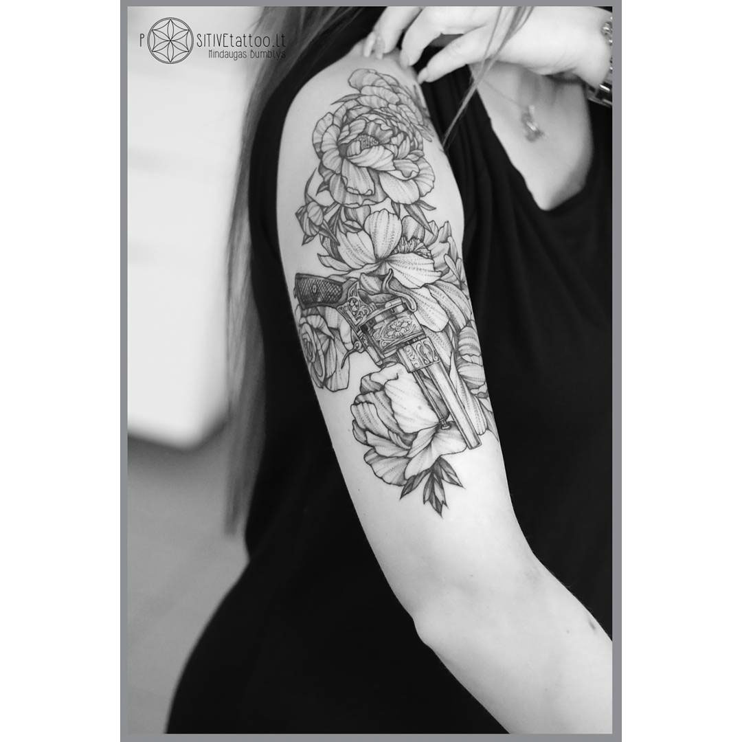 gun and flowers tattoo on shoulder